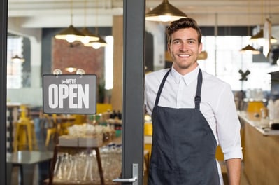 happy business owner standing outside of his restaurant