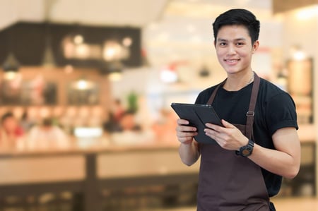 close up asian man holding tablet for checking order from customer on blurred coffee cafe shop background 