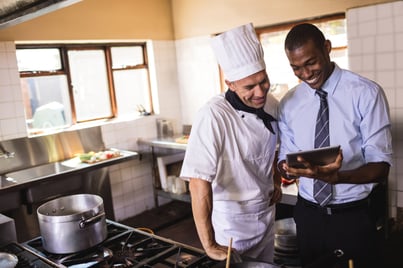 Male manager and chef using digital tablet in kitchen