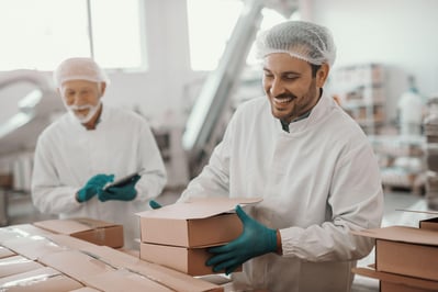 Smiling Caucasian employee arranging boxes while his superior using tablet and checking on him.