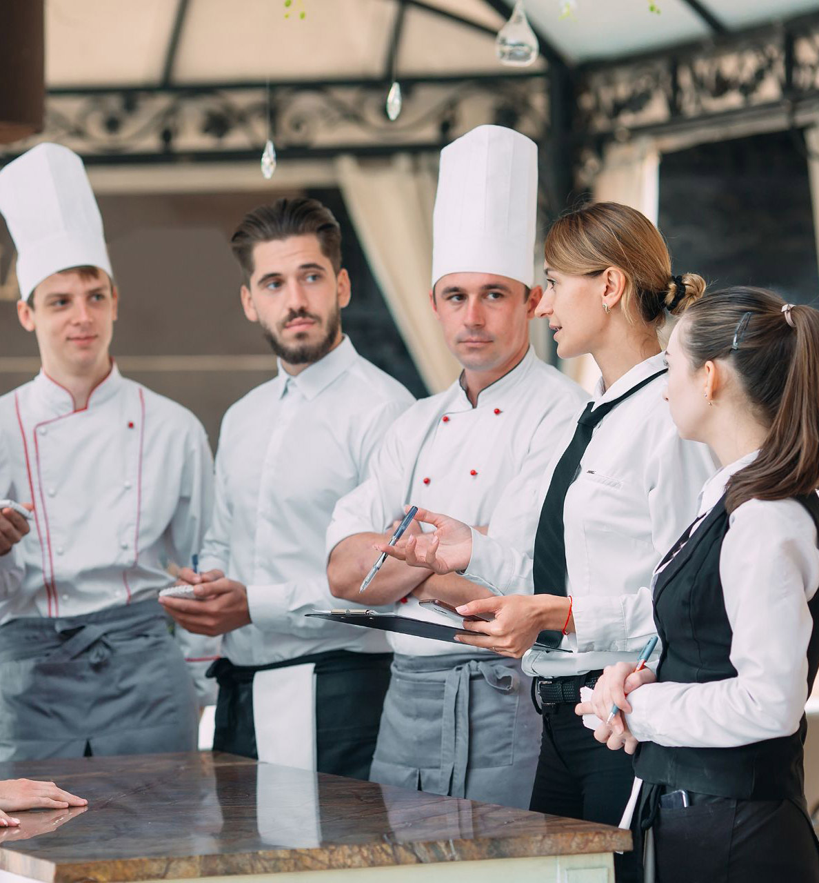 restaurant manager speaking with team of chefs